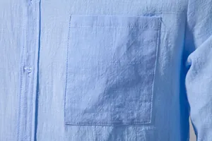 Close-up of chest pocket and fabric texture on a light blue cotton linen men's shirt