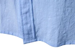Close-up of the fine stitching and breathable cotton linen fabric on a blue shirt hem