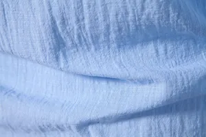 Macro detail of light blue cotton linen shirt fabric showing a breathable texture