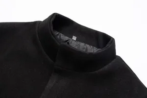 Detalle de un abrigo de lana negro para hombre que muestra el cuello alto y la tela