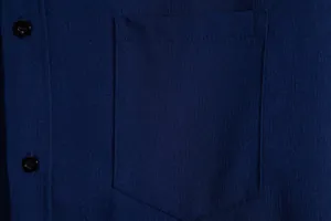 Close-up detail of pocket and navy blue fabric texture on men's casual button-down shirt