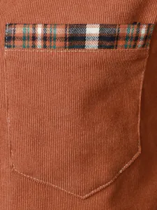 Dettaglio tasca camicia in velluto a coste con bordo a quadri a contrasto.