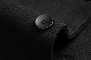 Detalle macro del botón y la textura de lana de un abrigo negro elegante para hombre