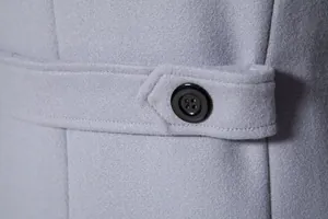 Macro view of grey wool trench coat fabric featuring black button and fine stitching detail