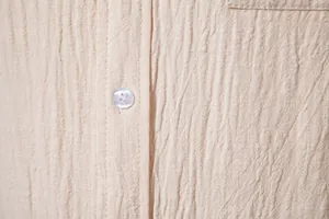 Close-up detail of men's apricot cotton linen shirt showing crinkled texture and button