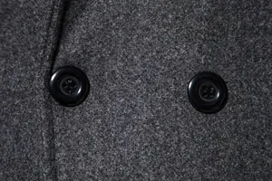 Close-up of grey wool fabric and black buttons on a men's double-breasted overcoat.