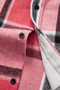 Primer plano de tela de franela a cuadros rojos y negros con textura de espiga y botones.