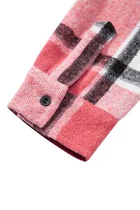 Detalle del puño de camisa de cuadros rojos con tejido de espiga y botón negro