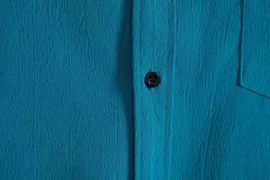 Detailed close-up showing the teal textured fabric and button of a men's casual shirt