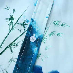 Détail rapproché montrant le bouton blanc et l'imprimé bambou sur une chemise hawaïenne