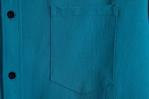 Close-up of teal men's casual shirt showing crepe fabric texture, pocket, and buttons.