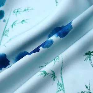 Vue macro d'un tissu bleu clair avec taches d'encre bleu foncé et bambous verts