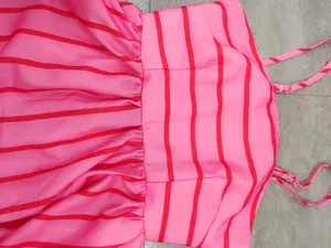 Close-up of gathered waist and straps on a pink and red striped summer sundress.