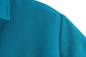 Detailed macro view of teal blue textured fabric on a casual short sleeve shirt