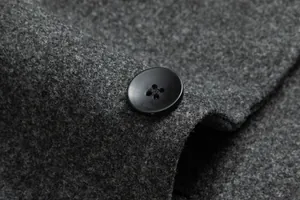 Primer plano de un botón negro en la textura de un abrigo de lana gris
