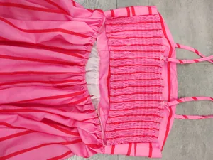 Close-up of pink and red striped dress featuring elastic smocking detail and straps.