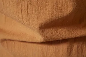 Close-up macro of breathable cotton linen fabric texture in orange-brown color
