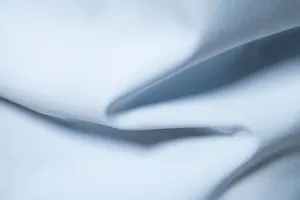 Macro detail of high-quality light blue smooth fabric texture for men's casual dress shirt.