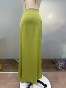 Close-up detail of a lime green satin maxi skirt showing elegant drape and silky texture