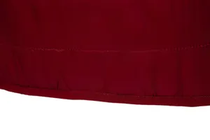 Close-up detail of high-quality stitching on the hem of a stylish burgundy winter jacket