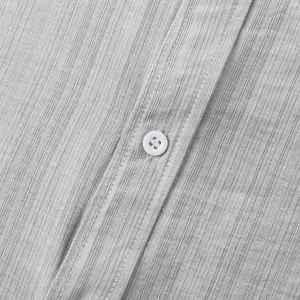 Detailopname van lichtgrijze getextureerde stof en witte knoop op een herenhemd