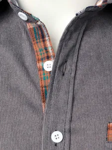 Dettaglio camicia da uomo in velluto a coste grigio con interno scozzese