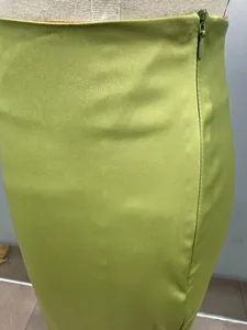 Detailed close-up view of invisible side zipper on an olive green satin midi skirt