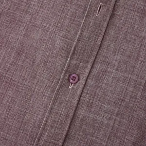 Macro detail of textured purple cotton linen shirt showing button and stitching