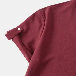 Detalle de la manga remangada con botón blanco en camisa de hombre color granate.