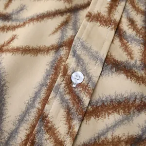 Gros plan montrant la texture du tissu et le bouton blanc d'une chemise hawaïenne fleurie.