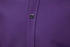 Close-up macro detail of a black button on a purple men's long-sleeved casual shirt.