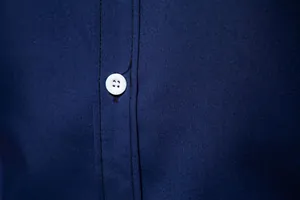 Macro detail of white button and dark blue fabric texture on Hawaiian casual shirt
