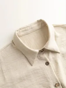 Close-up detail of a beige linen shirt featuring a lapel collar and dark wooden buttons