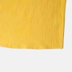 Macro view of men's yellow cotton linen shirt hem showing fabric texture and neat stitching