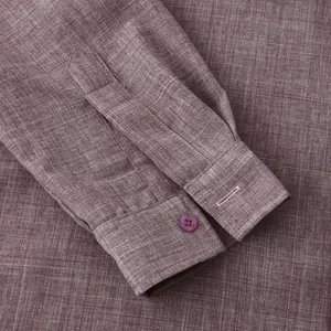 Macro detail of a maroon cotton linen shirt sleeve showing cuff and button