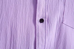 Macro detail view of purple crinkle fabric texture on men's casual shirt with button