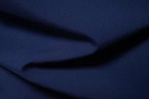 Macro detail of high-quality navy blue breathable fabric texture for men's beach shirts.