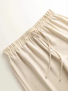 Detail view of the elasticated waistband with drawstring on these casual beige trousers.