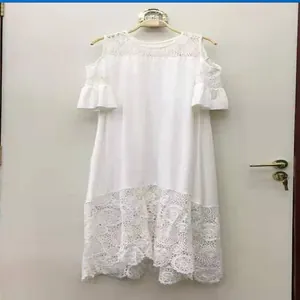 Dettaglio dell'abito bianco con inserti in pizzo e maniche con volant e spalle scoperte.