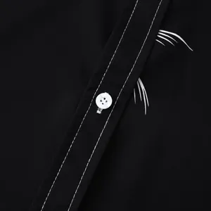 Détail d'une chemise hawaïenne noire montrant le bouton blanc, la couture et l'imprimé.