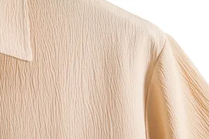 Detailed macro shot of beige crinkled fabric texture on a men's casual short sleeve shirt