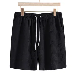 Close-up of men's black jacquard casual shorts with elastic waist and white drawstring.