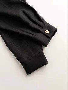 Detailed macro view of black linen-texture shirt cuff with wooden button