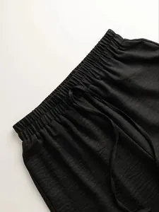 Detailed close-up of black casual pants showing elastic waistband and drawstring texture