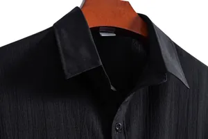 Detail of a black casual short-sleeve shirt with a subtle textured fabric and lapel collar.