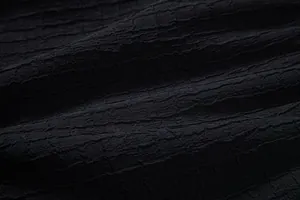 Macro close-up detail of premium black jacquard fabric texture with unique ripples