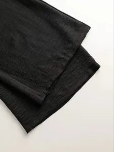 Close-up view of the black textured fabric on a stylish women's two-piece lounge set.