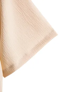 Detailed macro view of the textured beige fabric and hem stitching on a men's shirt