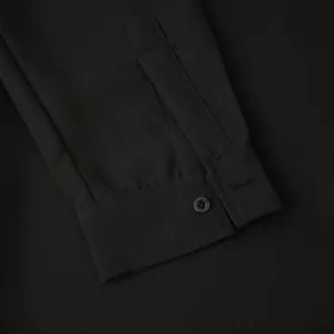 Detailed macro view of black linen shirt cuff showing high-quality stitching and button