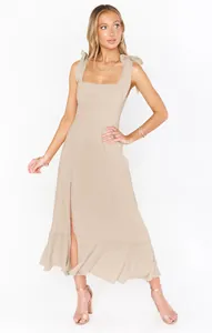 Elegant beige maxi dress with tie shoulders and a front slit, chic French style.